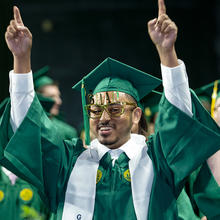 A graduate with cool glasses that say "grad" in gold.