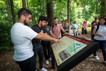 students read sign in wooded area