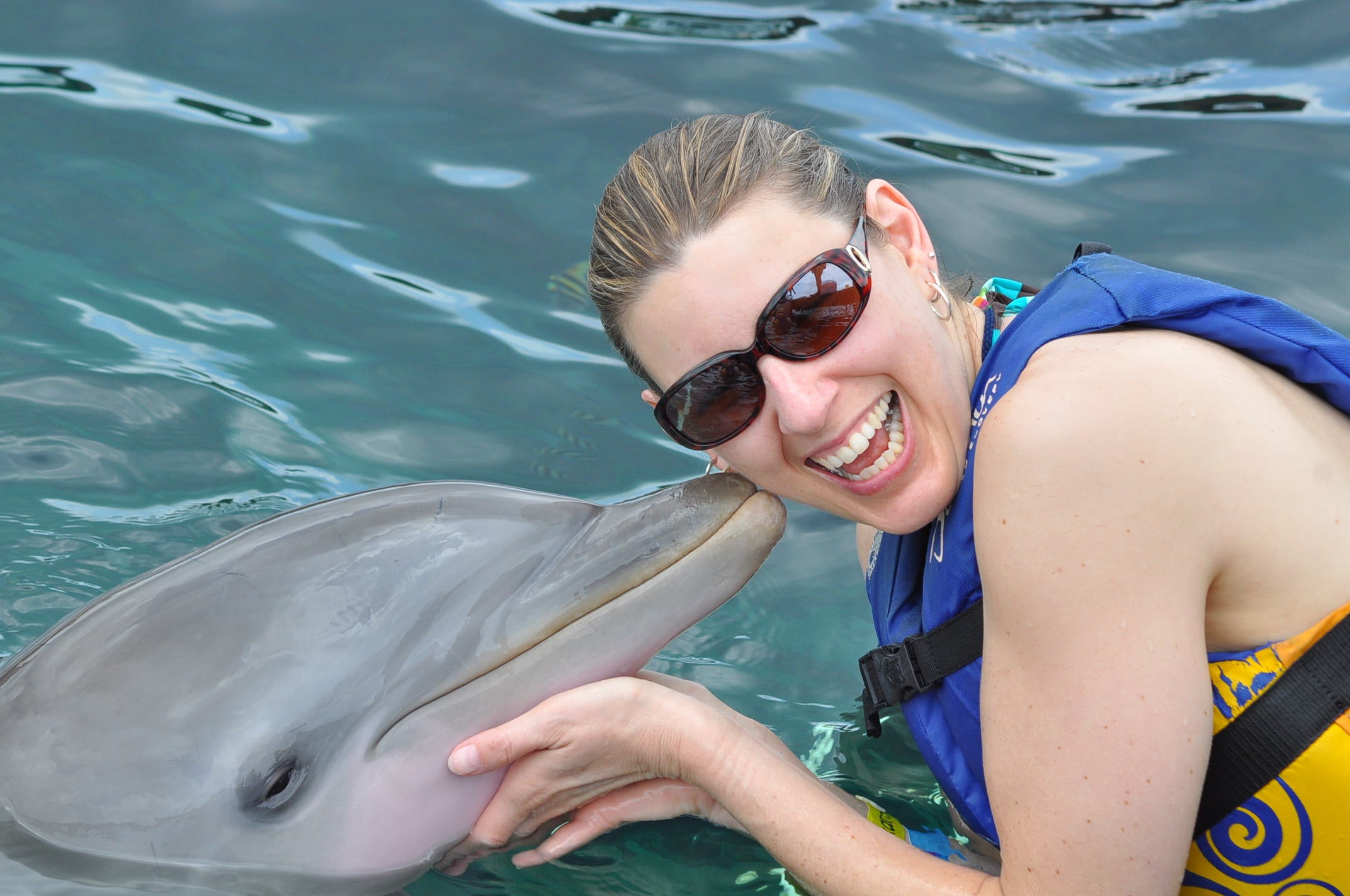 Traci Kendall smiles while she swims with a dolphin