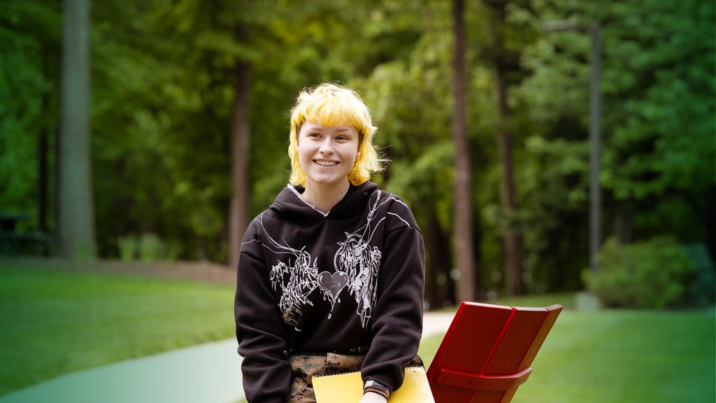 Mason student Sunny Sellers smiles while sitting in an adirondack chair on the Fairfax Campus.