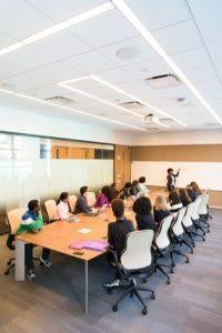 Large desk, conference style, with several people sitting around it.
