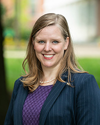 Melissa Broeckelman-Post is standing outside wearing a grey blazer and purple top