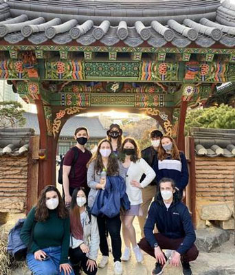 Students wearing masks in front of a gate at Mason Korea