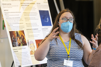 woman in mask in front of research poster