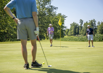 men on a putting green with golf clubs