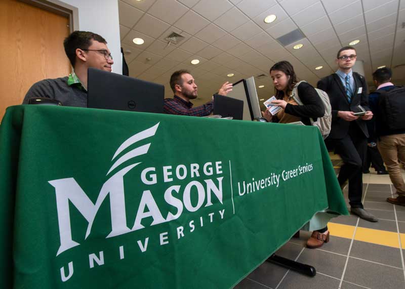 Personnel staff the George Mason University Career Services table at a recent career fair.