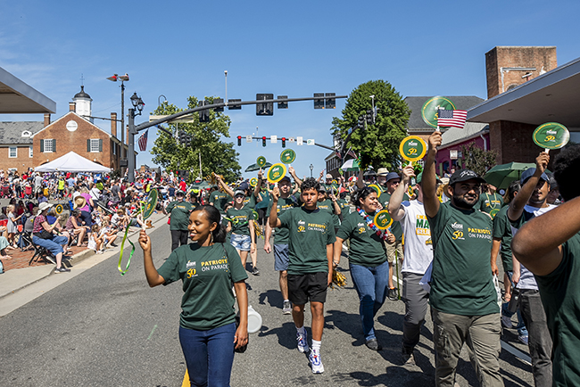 Members of Mason nation wear green shirts with Patriots on Parade and the 50th anniversary logo as they march in the City of Fairfax independence day parade.