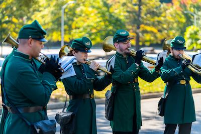 musicians in green period costumes play instruments