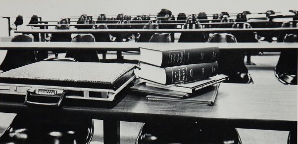 A briefcase and books stacked on a desk in a law classroom in 1980.