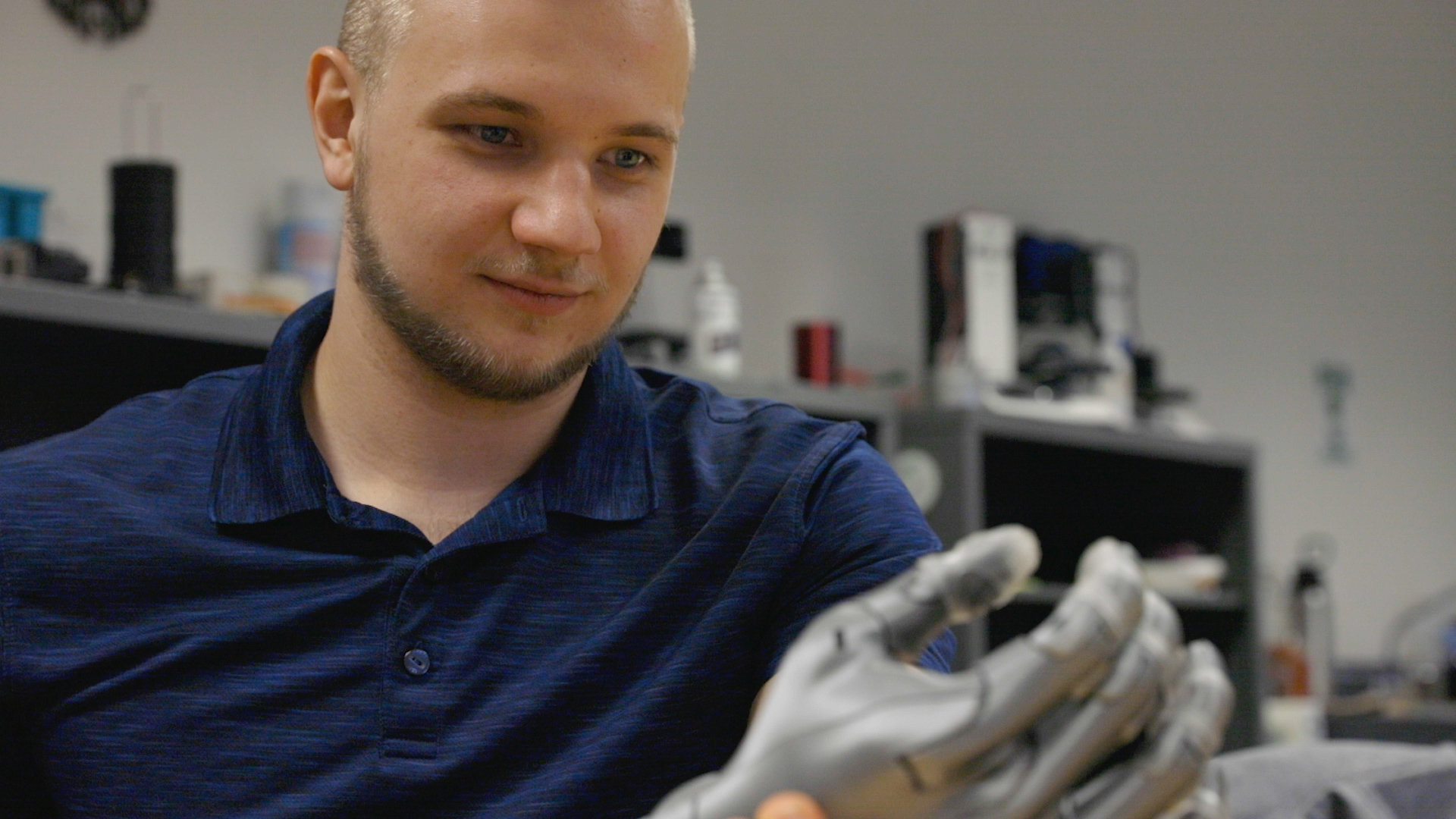 Denys Kuratchenko holding a prosthetic arm that he 3D printed.