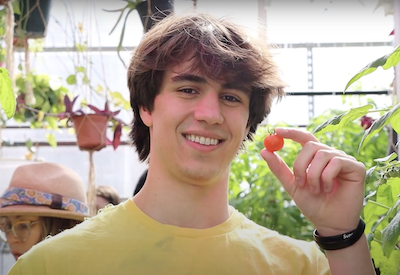 student with tomato in the greenhouse