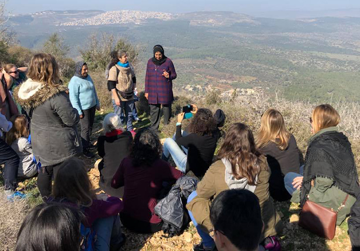 Mason students sit on a cliff as they listen to Arab and Jewish members tell stories.
