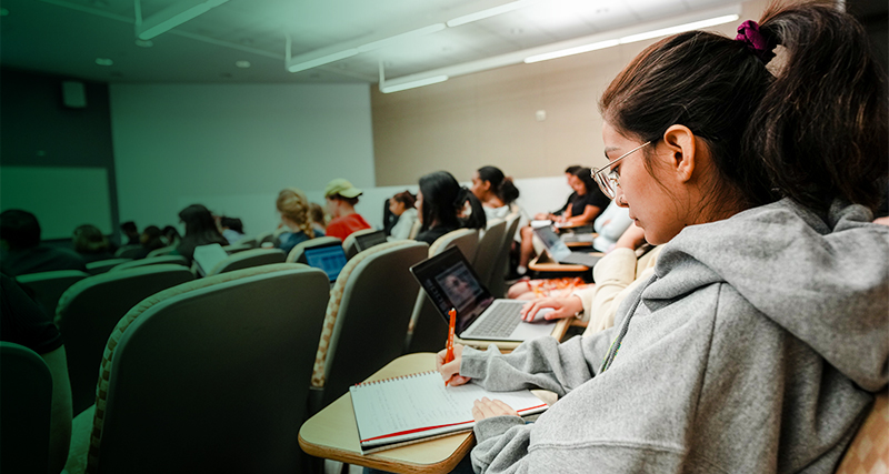 A transfer student takes notes in a Mason classroom