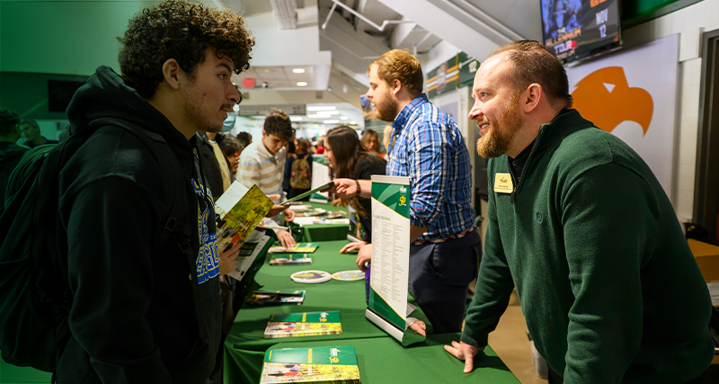 Mason admissions counselors meet and speak with prospective students at an event in EagleBank Arena