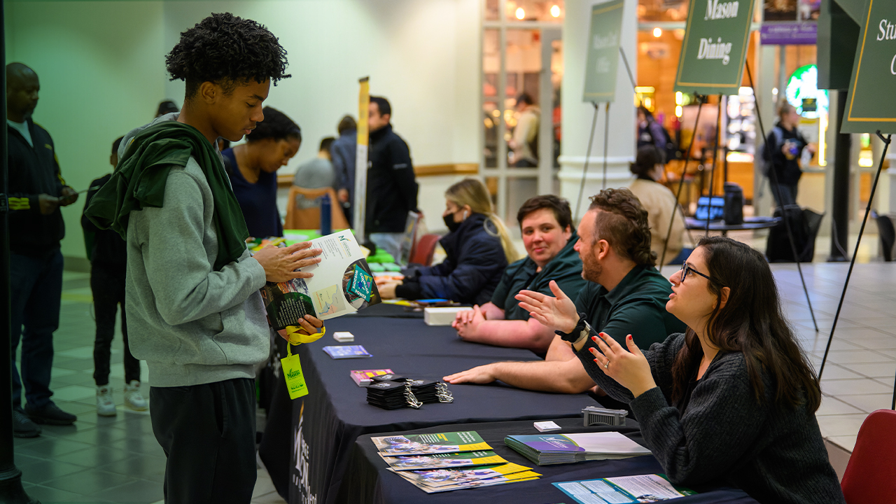 A prospective student reviews print materials at a Mason admissions event.