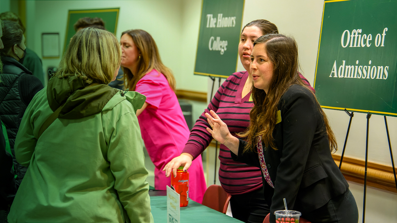 Mason admissions counselors speak with prospective students and their parents at an event.