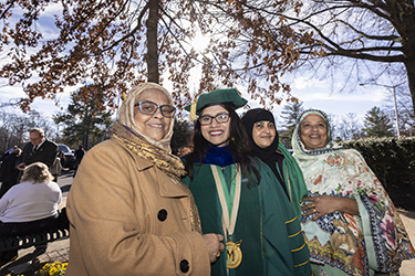 A graduate smiles for the camera with her family.