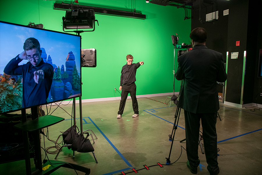 A guest poses in front of the green screen during a demonstration by the Film and Video Studies program at ARTS! By George 2022. (Photo by Cable Risdon Photography)