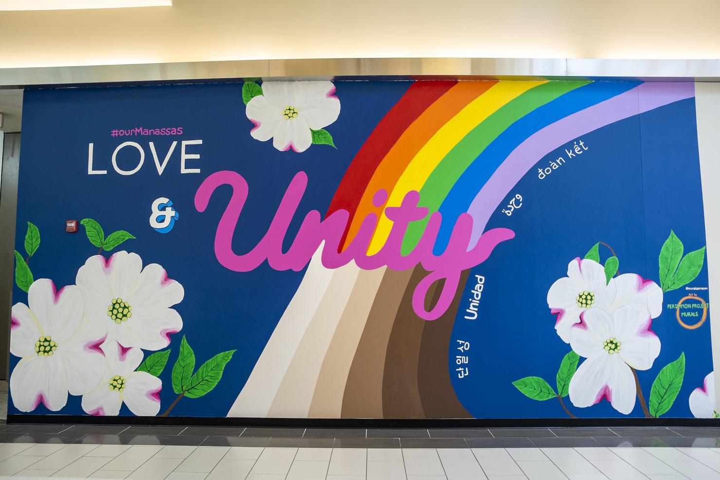 Mural says LOVE & Unity, with a rainbow, dogwood flowers, and the word "unity" in multiple languages