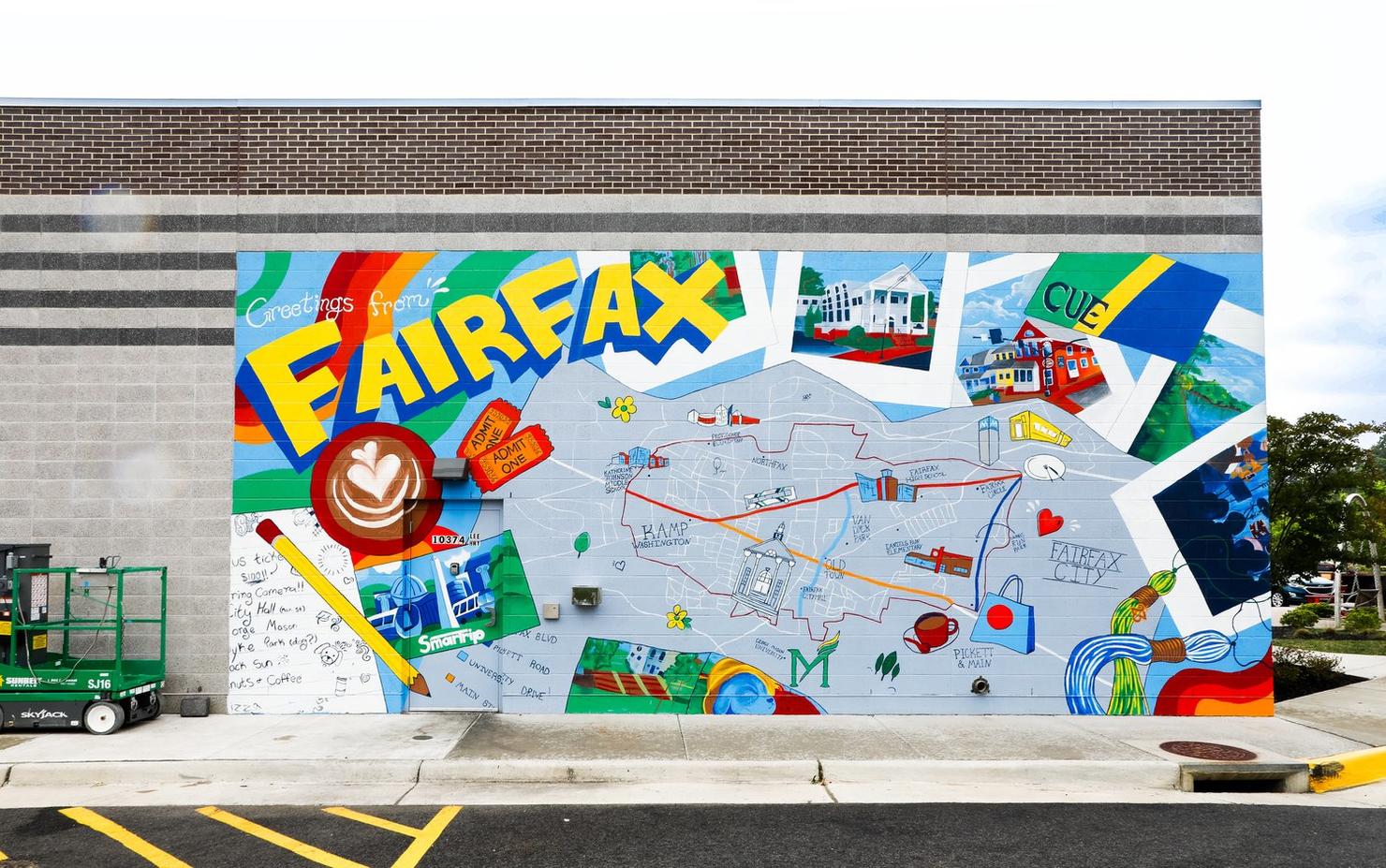 The 'Greetings from Fairfax' mural depicts a map of Fairfax City, with illustrations of important landmarks. The photo shows the mural on the exterior side wall of a restaurant