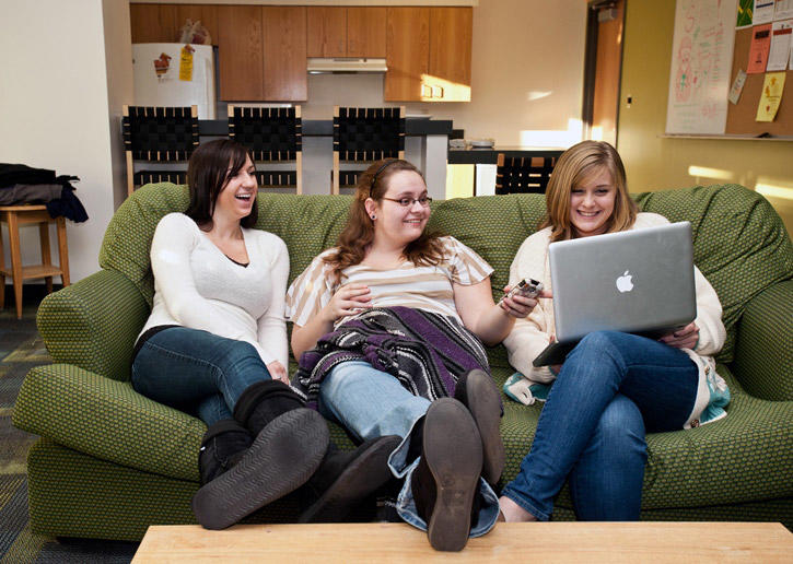 Students laugh with their feet up, looking at a computer