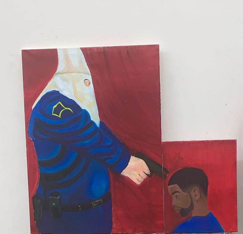 A white police man with a white cone shaped hood stands over a Black man. The White man is pointing a gun at the head of the kneeling Black man.