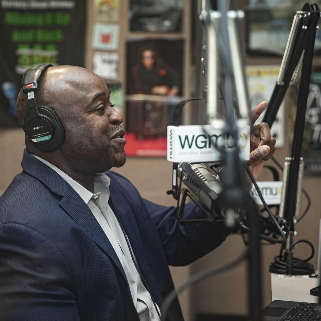 President of George Mason University, Gregory Washington, speaking into a mic in a recording studio, recording his podcast Access to Excellence