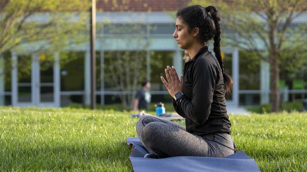 student sits on the lawn practicing meditation