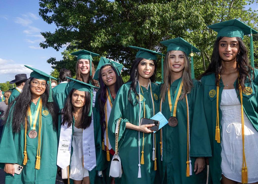 Seven female students from the College of Engineering graduation day. They are dressed in mason colors cap and gown.