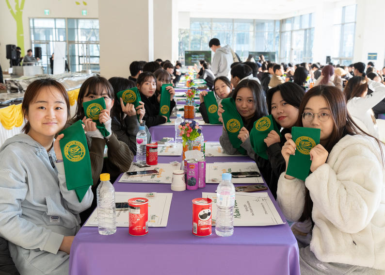 Students at Mason Korea hold up banners for 2024 Student Convocation welcoming the largest Mason Korea class.
