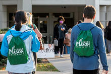 Students wearing Mason backpacks walk toward Johnson Center on Fairfax Campus