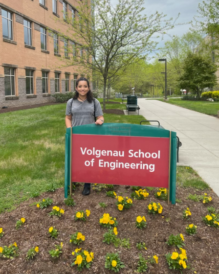 Caitlin Parra standing in behind a Volgenau School of Engineering sign outside the engineering building. 