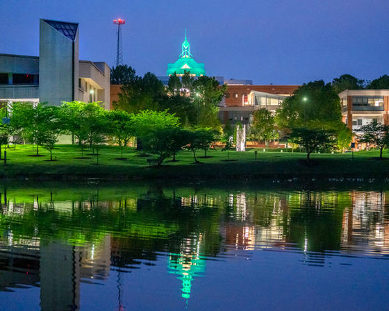 Illuminated spier of the Johnson Center at George Mason University Fairfax campus, reflected in Mason Pond.