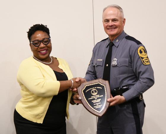 Samantha McClelland, George Mason University staff, accepts the Motor Vehicle Safety Award plaque from a Virginia State Police officer.