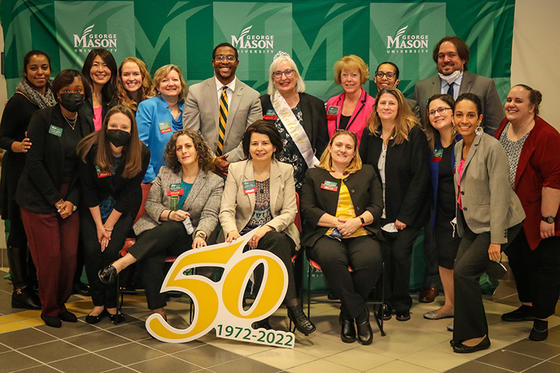 Approximately 20 University Career Services staff are shown in front of a Mason backdrop