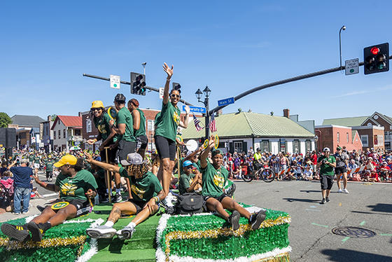 Mason basketball coach Vanessa Blair Lewis and members of the women's basketball team dressed in green Mason T-shirts on the Mason float for the Fairfax City July 4 parade