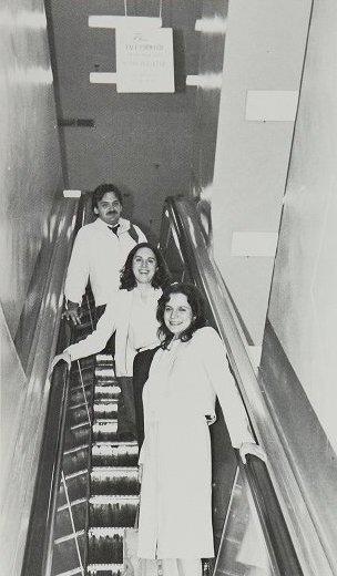 Three law students riding a down escalator. 
