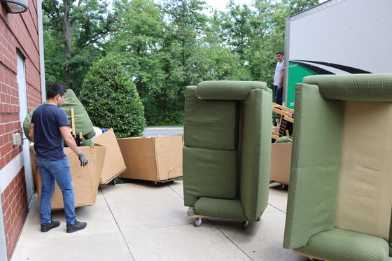 Couches are loaded on furniture dollies outside a residence hall on the Fairfax Campus, with a moving truck parked nearby