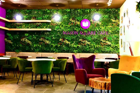 Mason Square Cafe is decorated with a wall of greenery, with dark velvet armchairs and contemporary furniture
