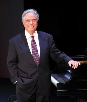 Pianist Jeffrey Siegel stands with his hand on a piano