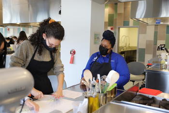 Image of two Mason community members cooking healthy recipes in the Nutrition kitchen