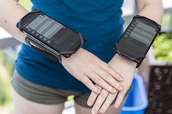 Cell phones are strapped on a student's wrists as signs.